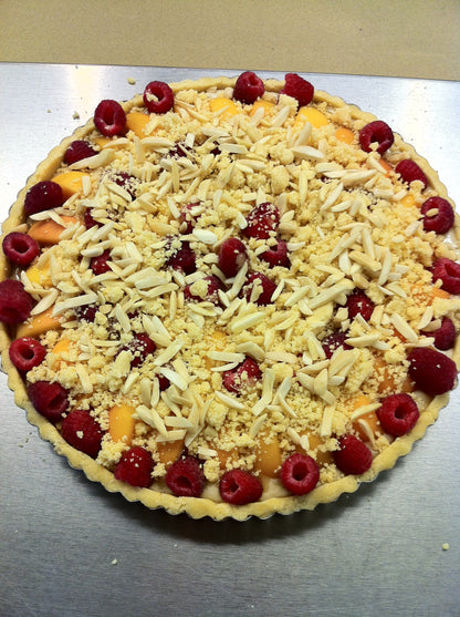 Unbaked tart with fruit and crumb topping on a metal surface